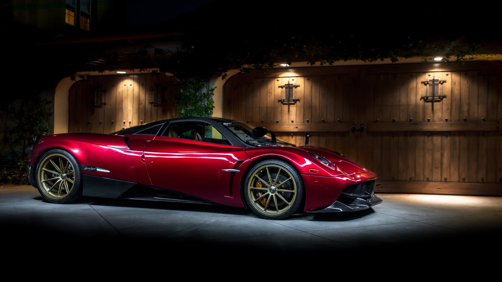A striking red Pagani Huayra supercar parked in front of a wooden gate, showcased in 4K Ultra HD as a PC desktop wallpaper and background.
