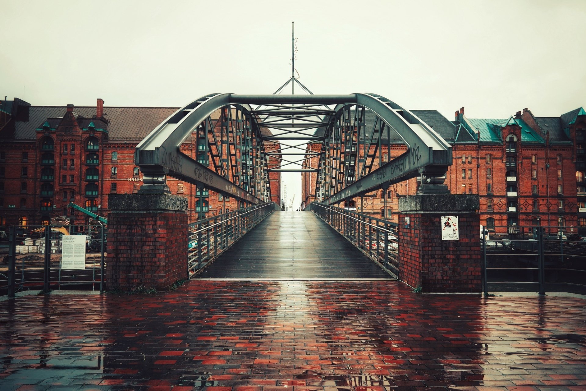 Steel bridge in Hamburg, Germany, captured in high-definition with historic red brick buildings lining the background under an overcast sky.