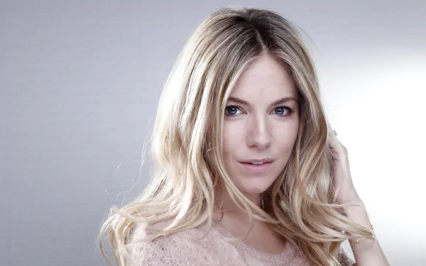 Close-up HD desktop wallpaper of American celebrity model Sienna Miller with blue eyes and blonde hair against a soft neutral background.