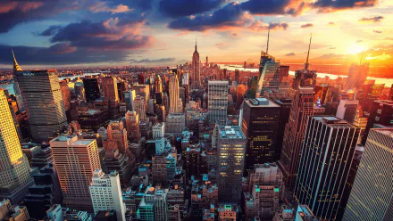 A stunning HD desktop wallpaper of New York City, showcasing a sprawling cityscape filled with towering skyscrapers under a dramatic sunset sky in the USA.