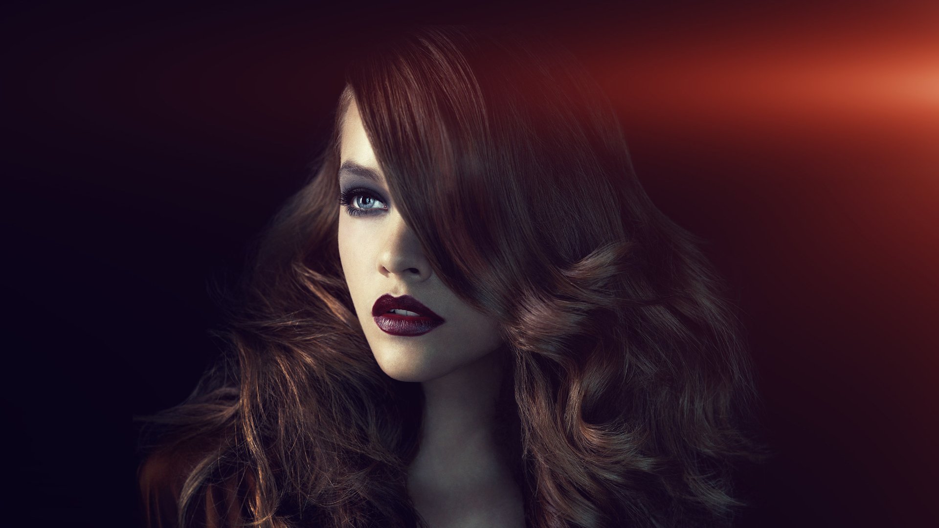 HD desktop wallpaper featuring a close-up of brunette Hungarian model Barbara Palvin with striking blue eyes and dark lipstick against a dark, softly lit background.