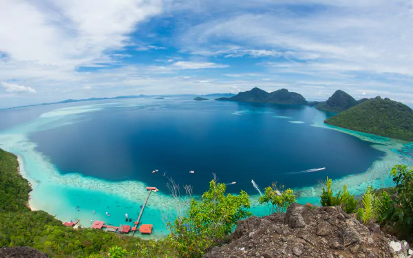 HD desktop wallpaper featuring a stunning fisheye view of the ocean and lush greenery along the coastline in Malaysia. Vibrant blues and greens capture the serene beauty of nature and the sea.