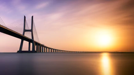 Vasco da Gama Bridge in Portugal stretches over calm water at sunset, captured in a 4K Ultra HD desktop wallpaper and background.