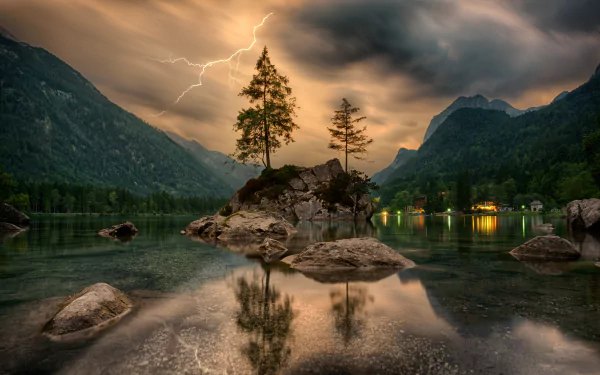 A stunning HD wallpaper featuring a serene island in a tranquil lake, framed by towering mountains. The dramatic sky is illuminated by a lightning strike, adding to the breathtaking natural scenery.