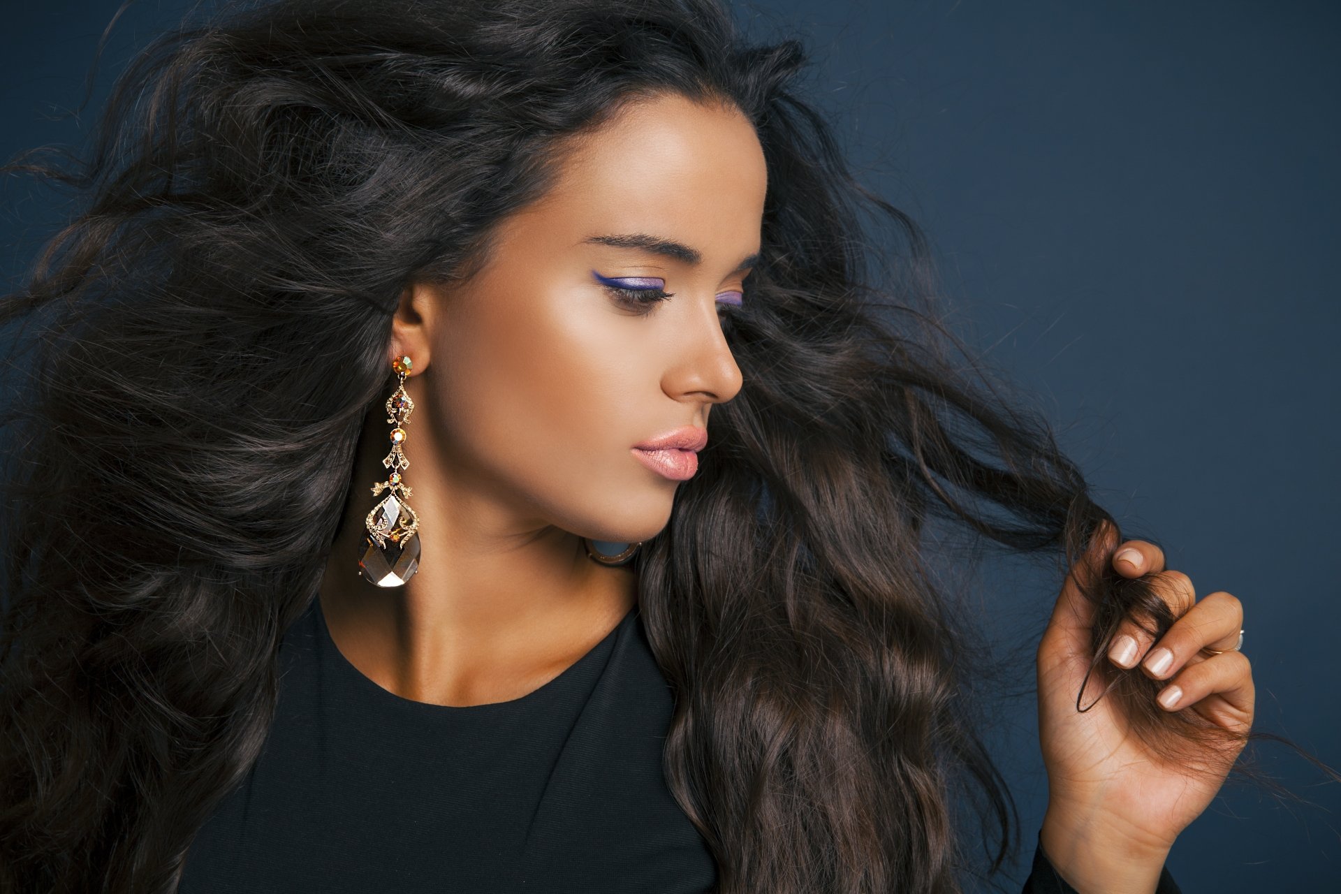 Wind-swept dark-haired woman model in profile wearing dangling earrings, glossy skin and flowing hair — 5K Ultra HD PC desktop wallpaper/background.