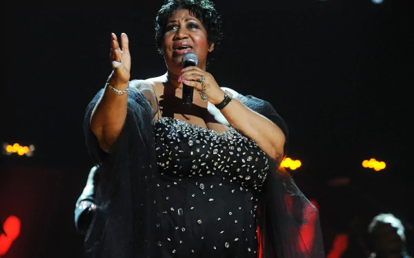 Aretha Franklin captivates on stage, microphone in hand, delivering a powerful performance. This HD desktop wallpaper celebrates her iconic presence in music.
